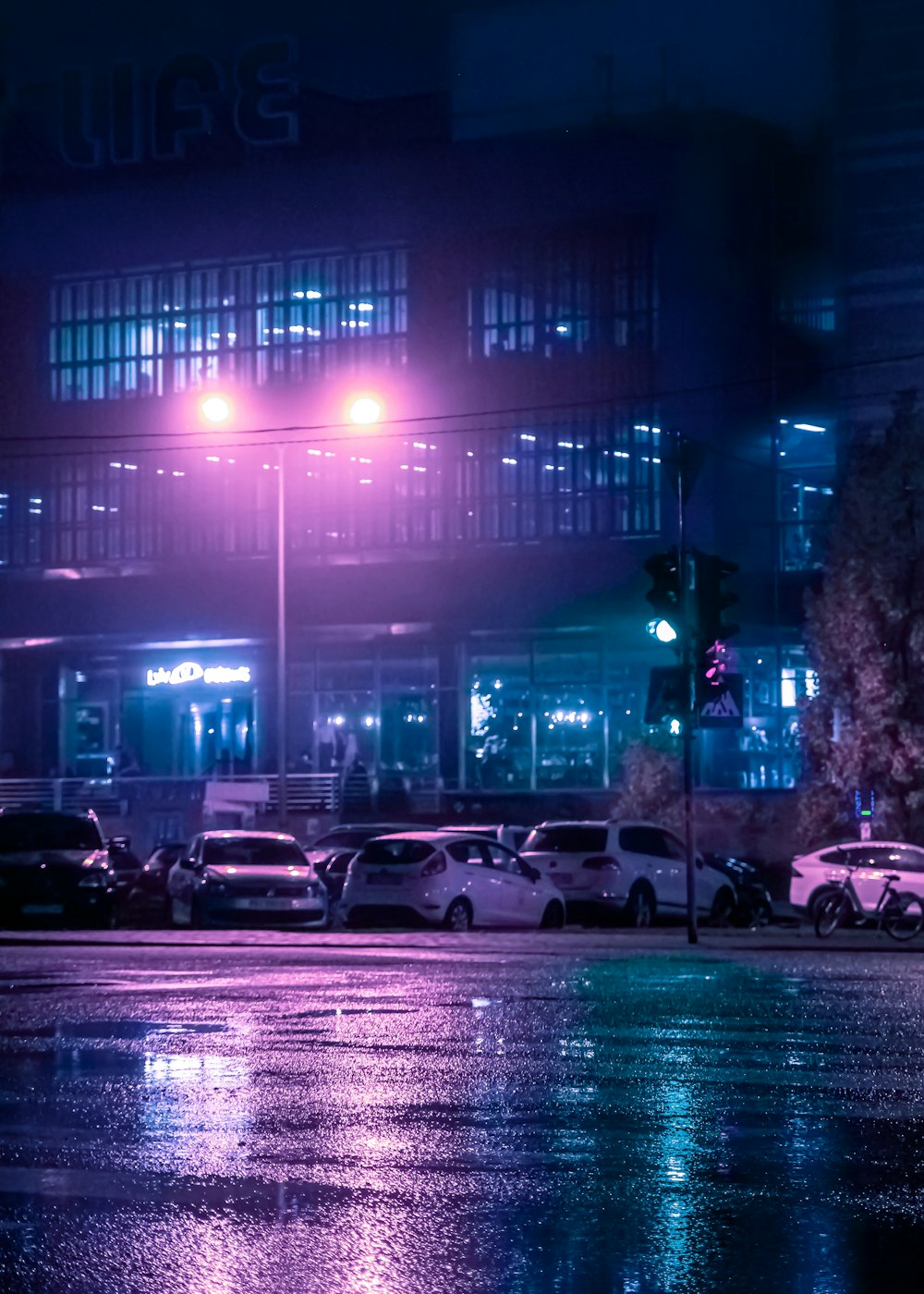 a city street at night with cars parked on the side of the road