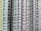 Several spiral-bound notebooks are arranged vertically side by side. The focus is on the spines, which are made of wire binding in various colors, including white, black, and gray. The covers of the notebooks display a range of colors such as yellow, green, and blue.