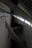 Concrete beams intersect at various angles within a minimalist, industrial space. Natural light filters through a row of windows, casting geometric shadows on the walls.