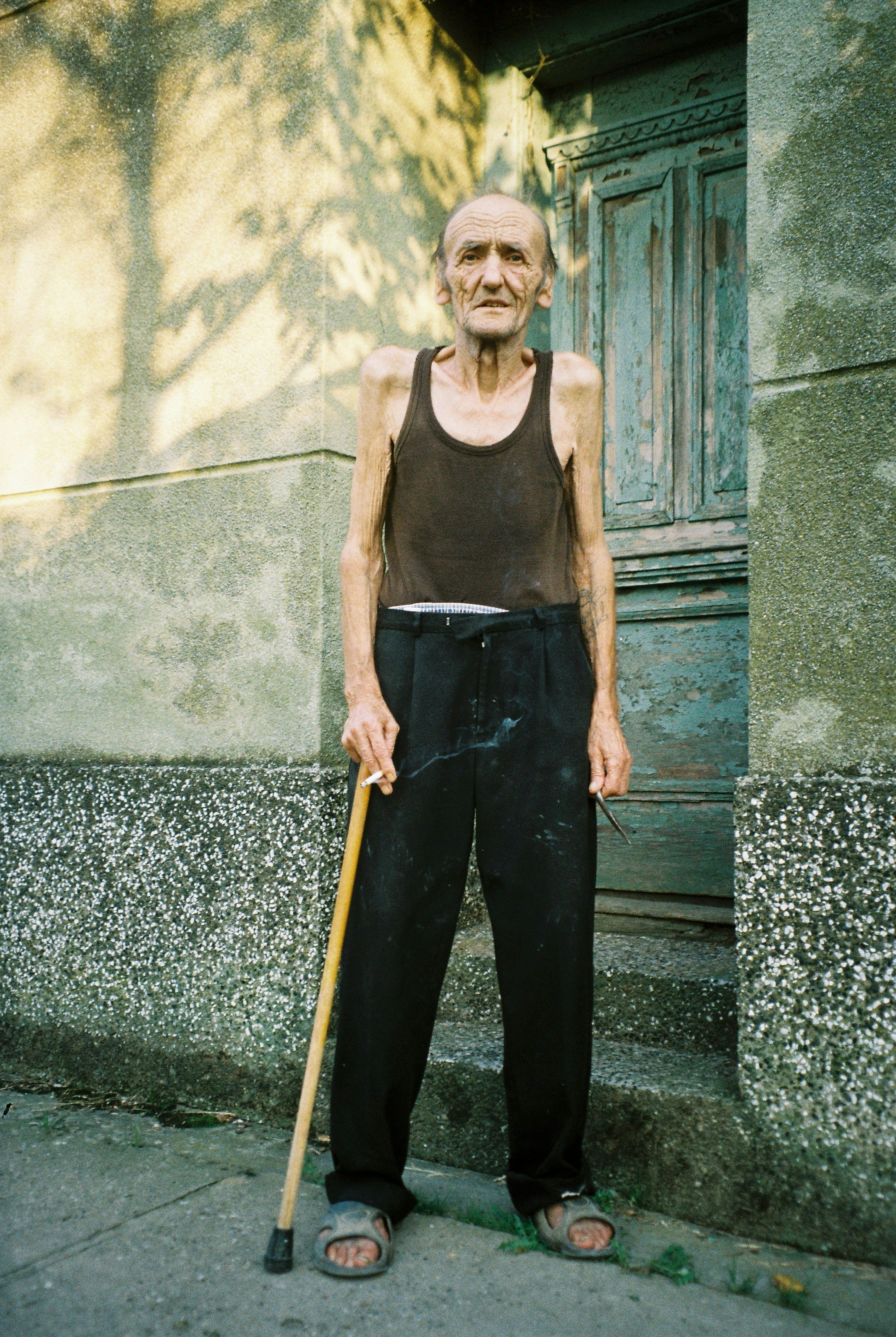 an old man with a cane standing in front of a building