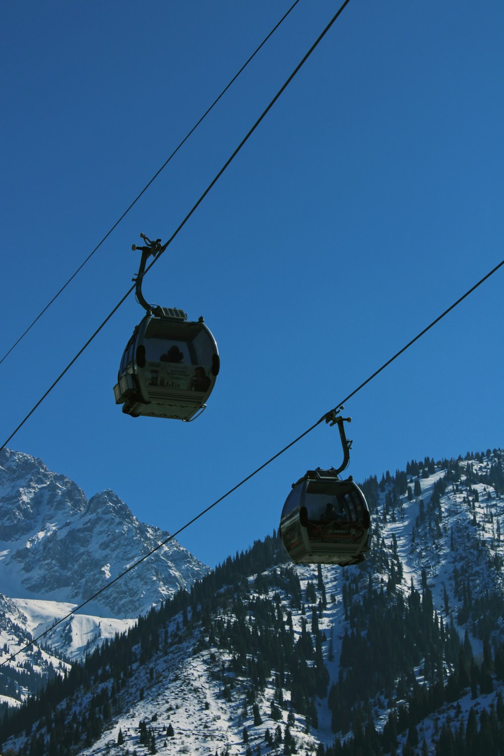 a couple of gondolas hanging over a snow covered mountain