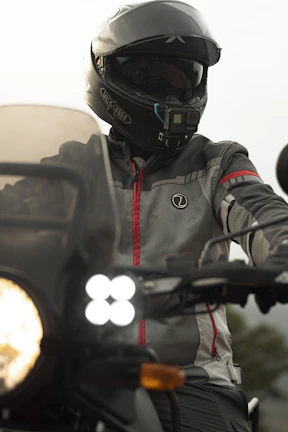 Motorcyclist wearing a helmet, with a GPS tracker visible on the bike