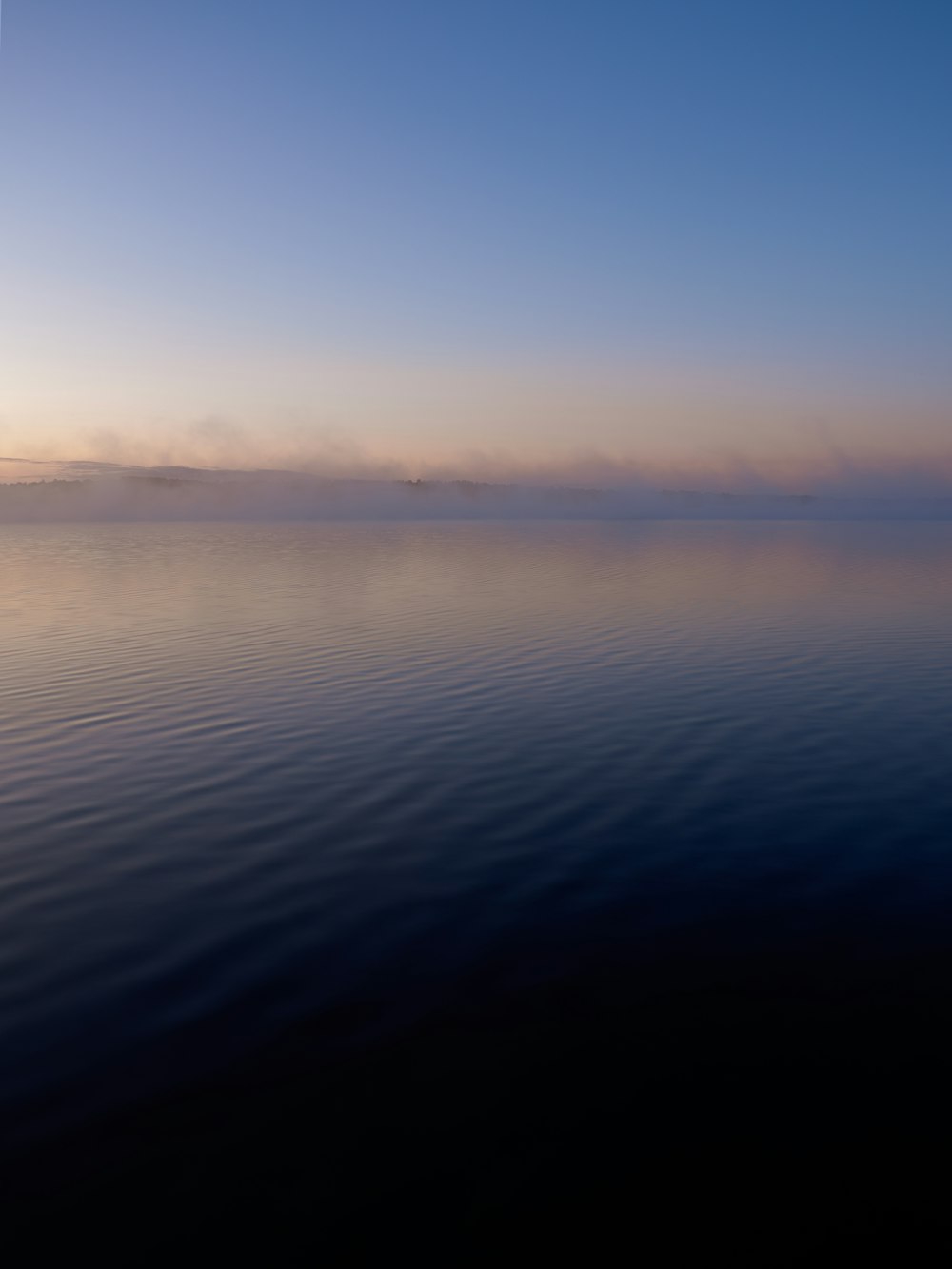 a large body of water with a sky in the background