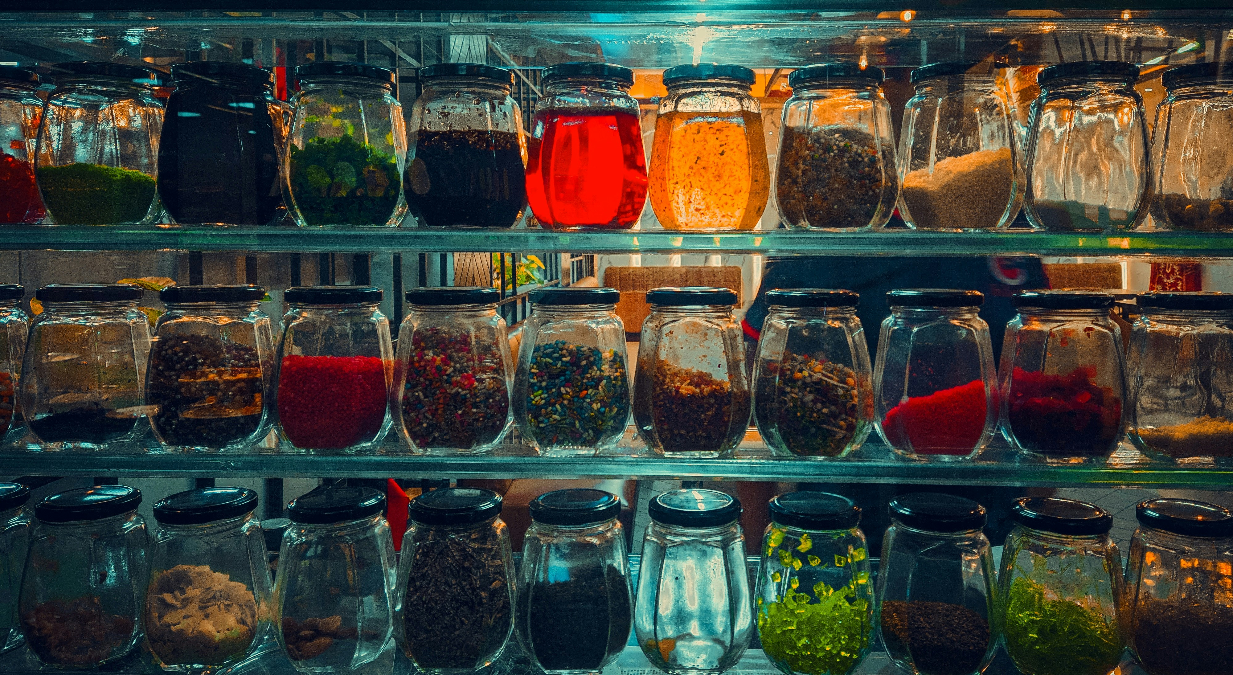 Potes de vidro com temperos e especiarias coloridas a granel em mercado, ambiente quente e acolhedor com iluminação natural