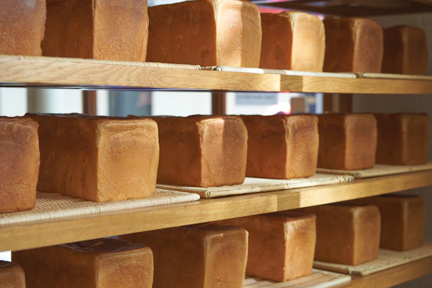 Warm bakery interior with fresh bread loaves cooling on wooden shelves.
