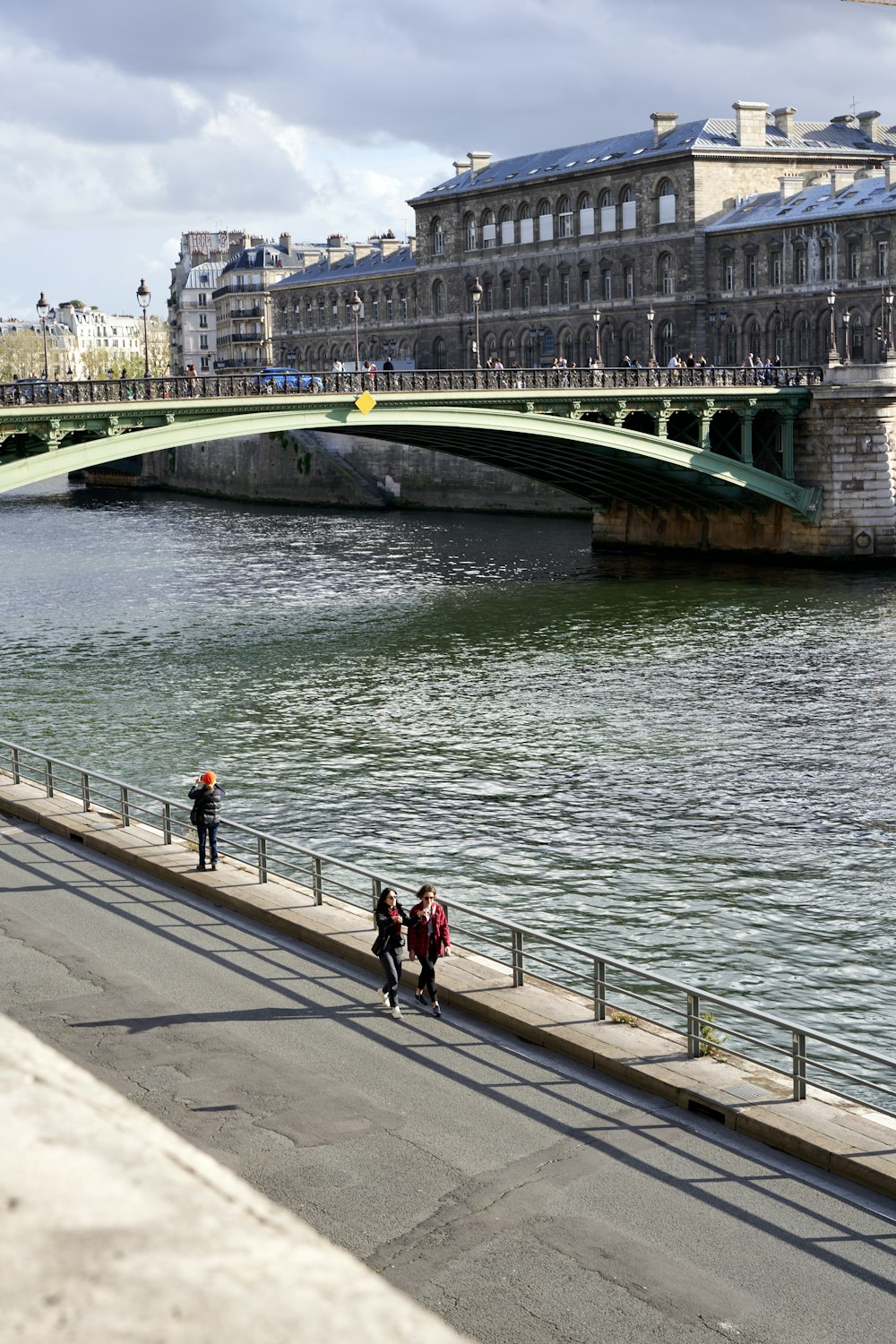 a group of people walking down a sidewalk next to a river