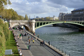 a group of people walking down a sidewalk next to a river
