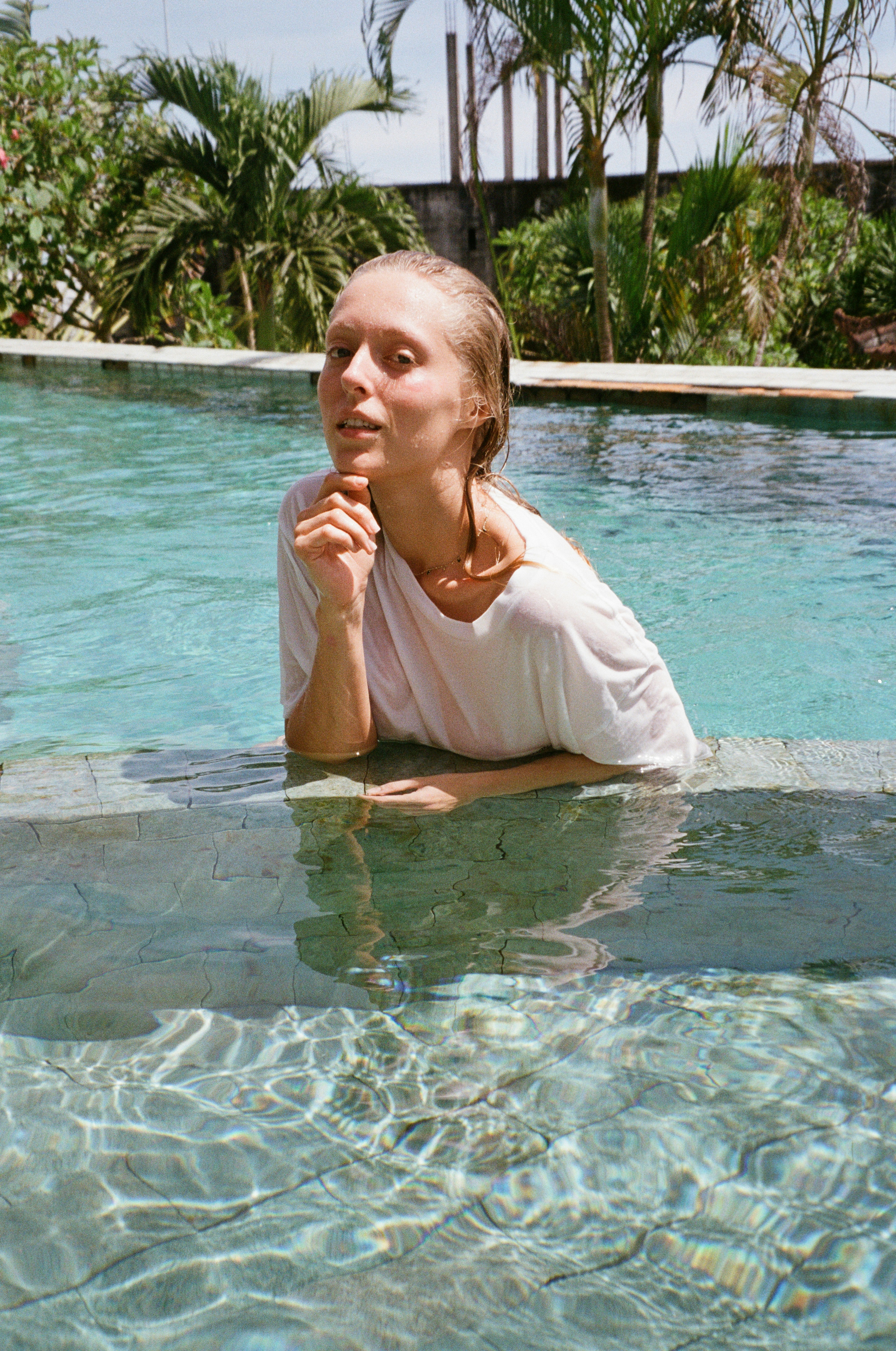 a woman sitting in a pool with her hand under her chin