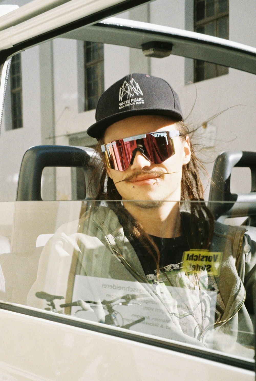 a man wearing sunglasses and a hat sitting in a car