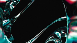 Fluid, metallic-like structures with a shiny surface swirl and curve against a dark background. The surfaces reflect light in a gradient of colors, giving an impression of movement and fluidity.