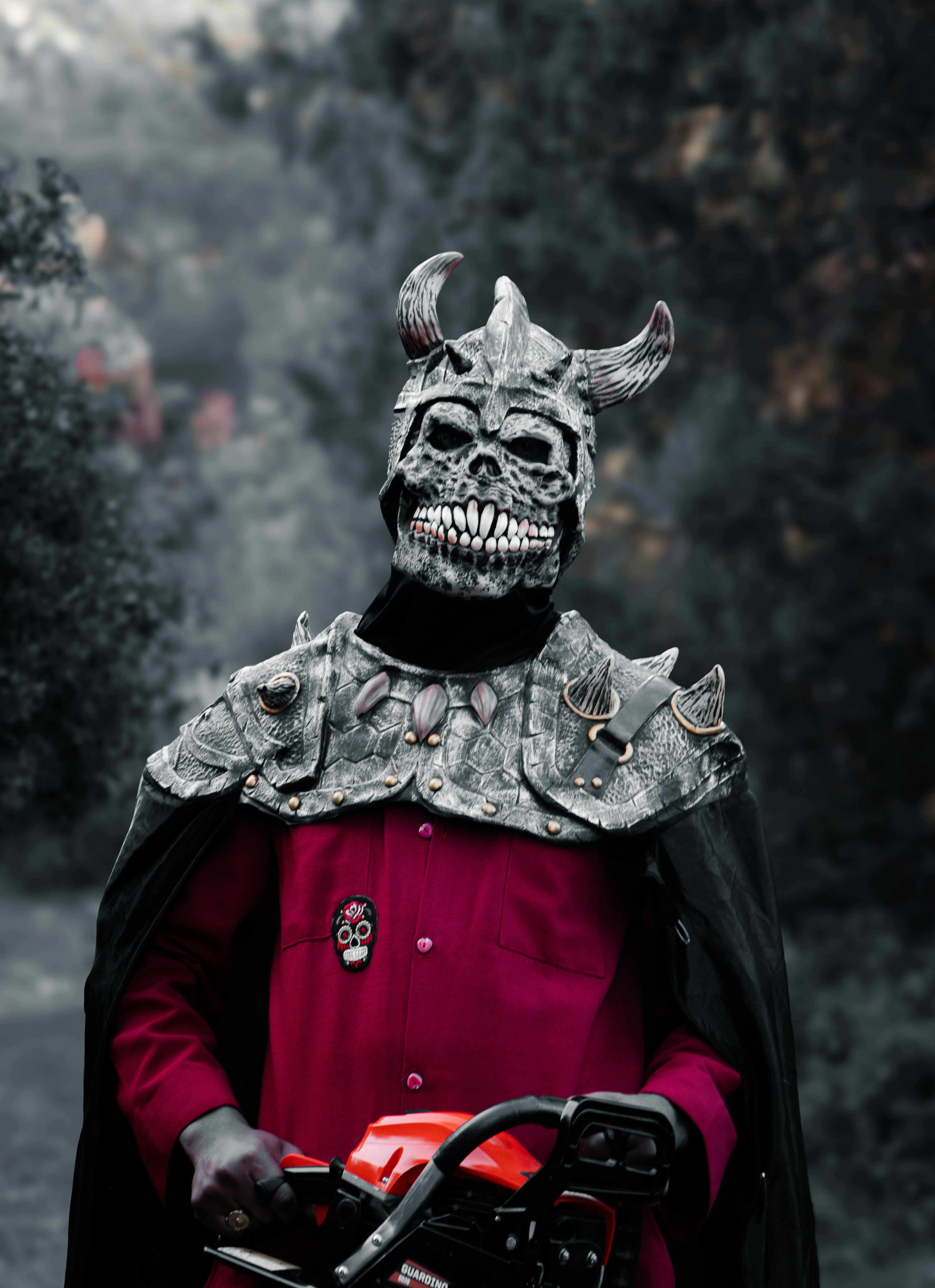 a man in a devil mask holding a chainsaw