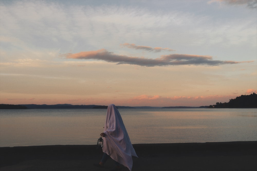 a person walking on a beach with an umbrella