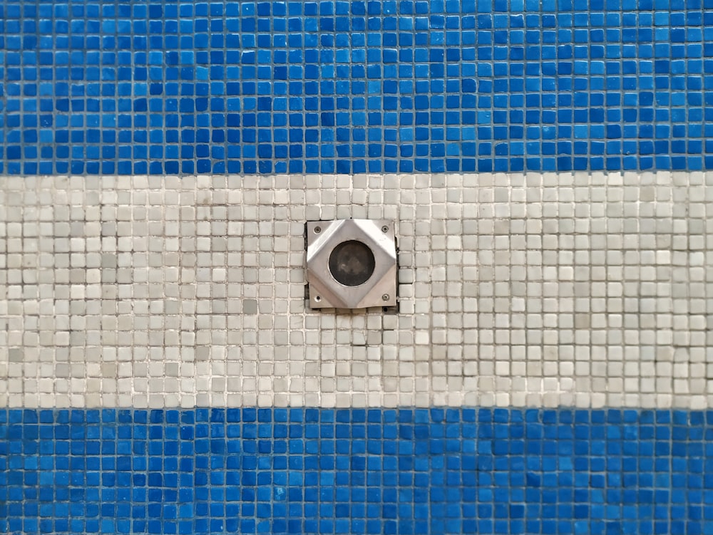 a blue and white tiled wall with a vent in the center