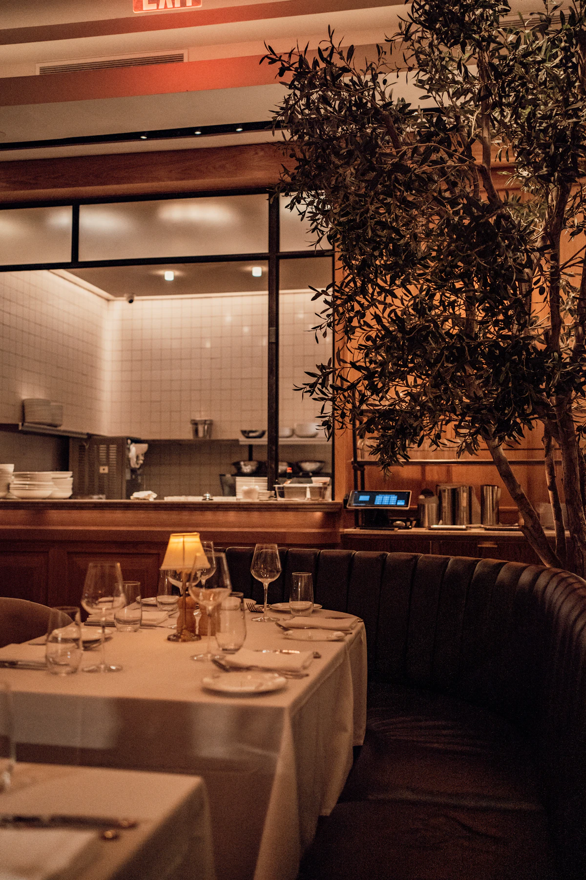 A narrow dining room with a lit counter and a row of stools, evening light low, at Sablé.