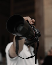 A professional photographer capturing a bride and groom during a wedding ceremony with a Sony camera.