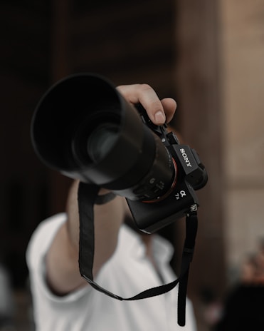 A professional photographer capturing a bride and groom during a wedding ceremony with a Sony camera.