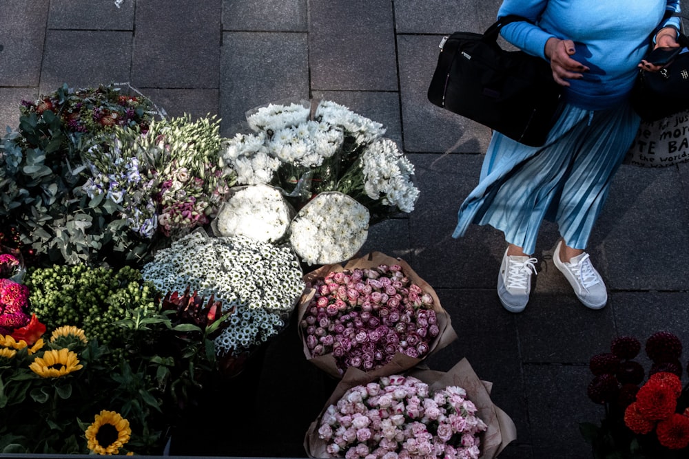 a woman walking past a bunch of flowers
