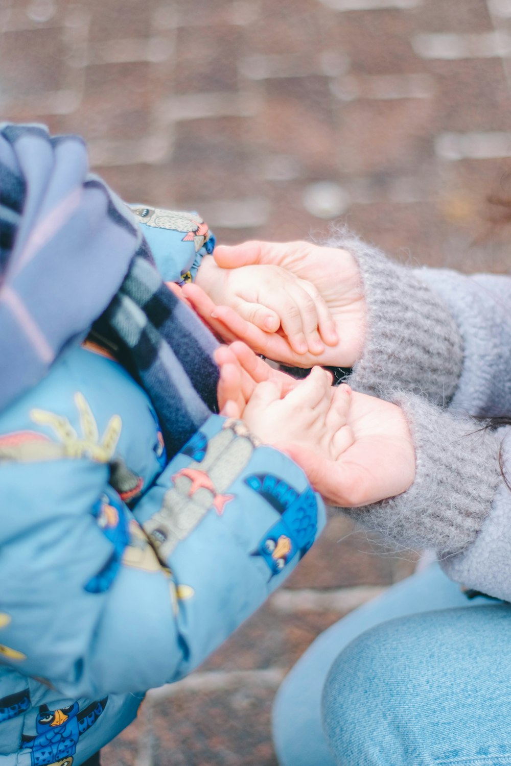 a baby in a blue jacket is holding a cell phone