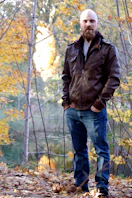 a man standing in the leaves in a wooded area