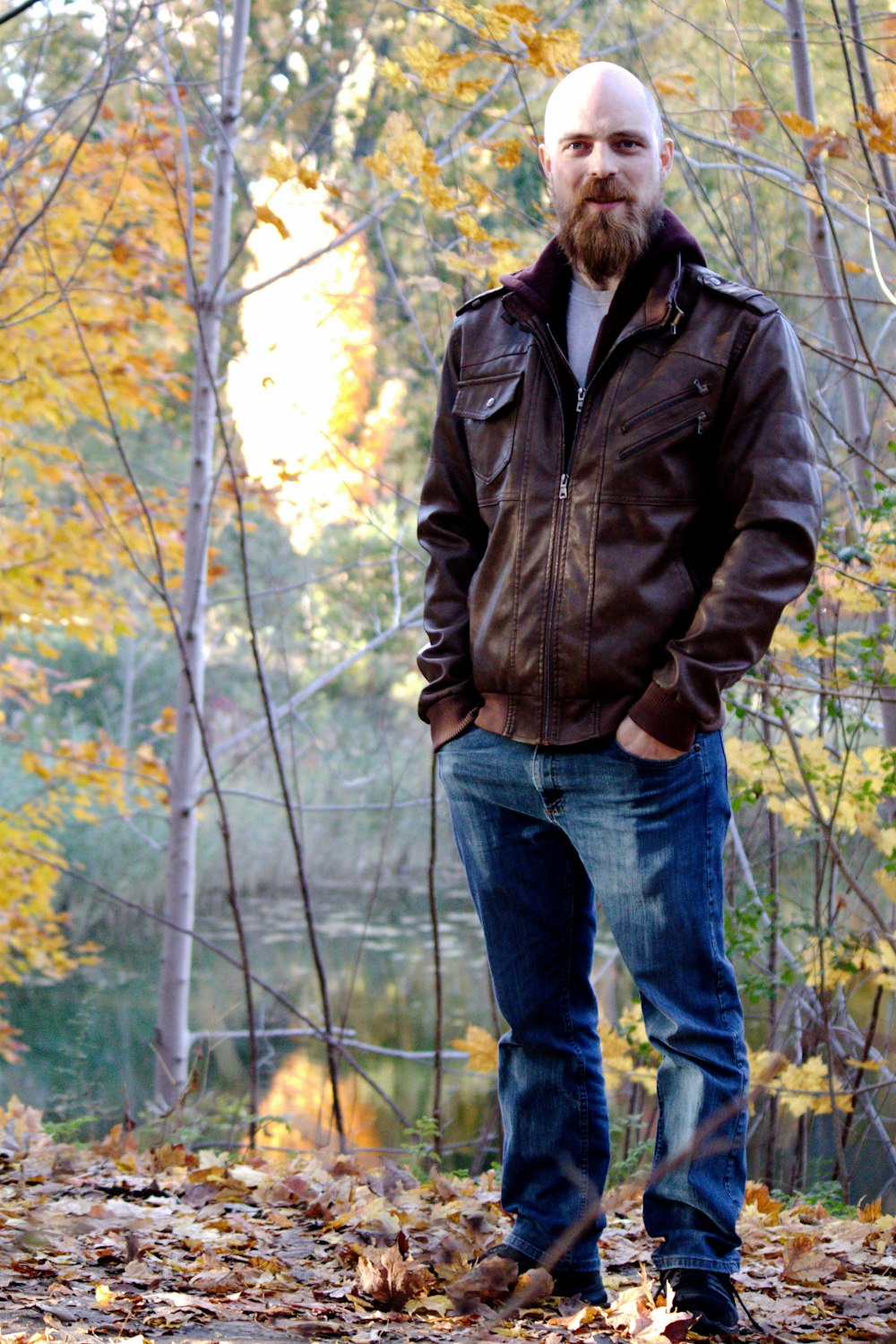 a man standing in the leaves in a wooded area