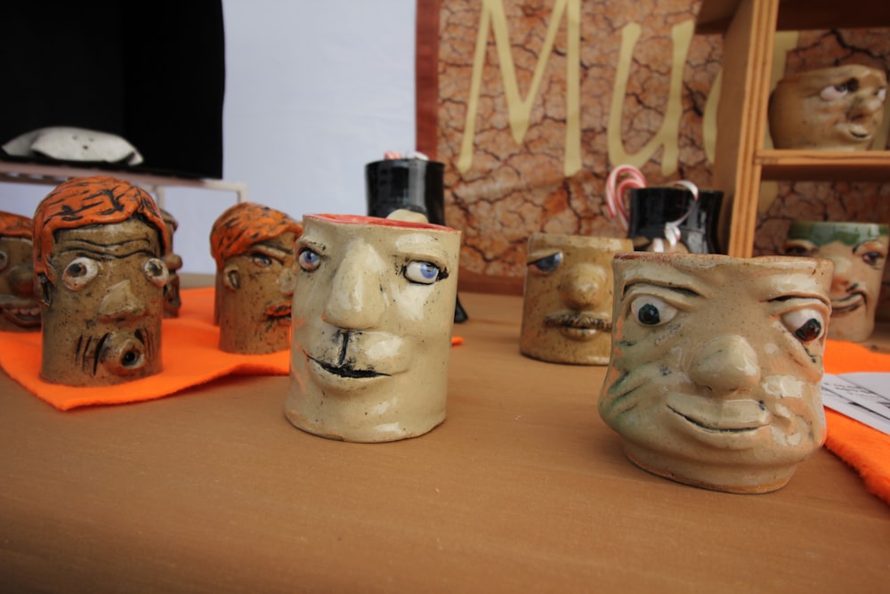 une table surmontée de visages et de tasses en céramique