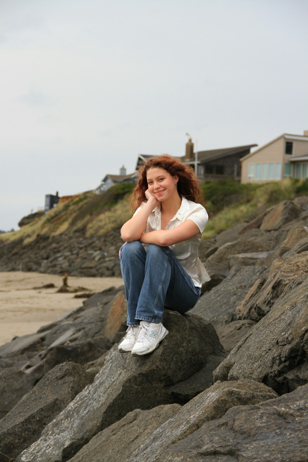 a woman is sitting on a rock by the water