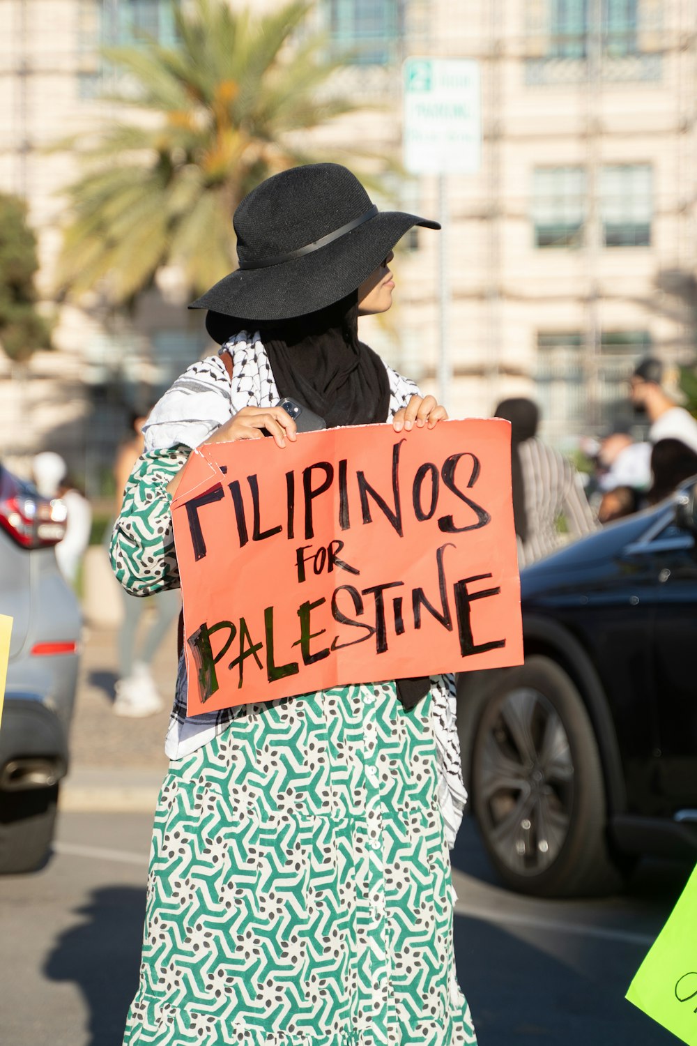 a woman holding a sign that says filipinos for palestine