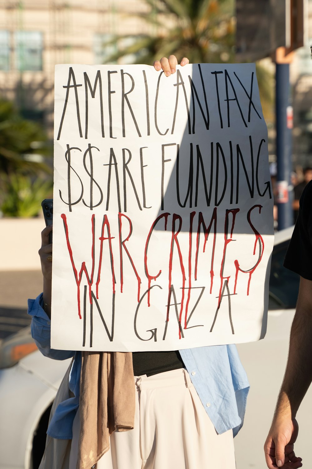 a man holding a sign that says war crime?