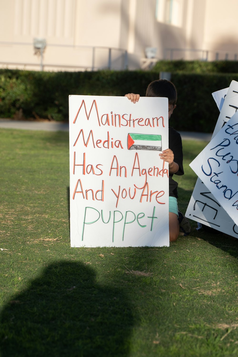 a young boy sitting on the grass holding a sign