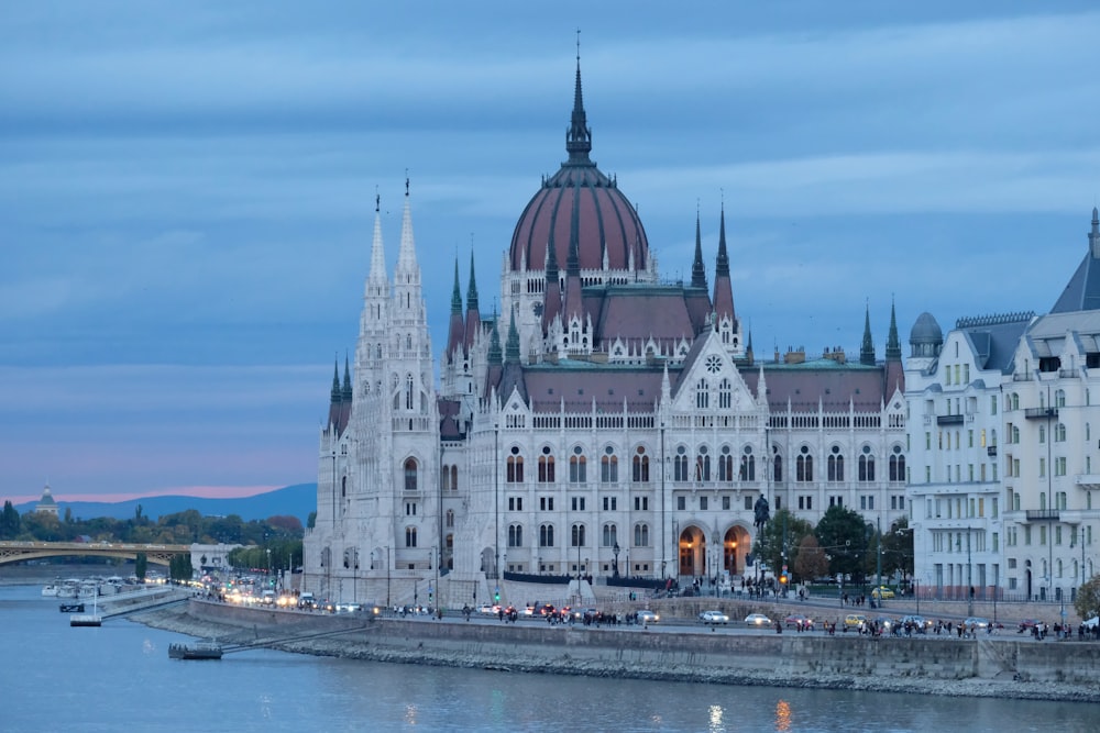 a large white building with a red dome next to a body of water