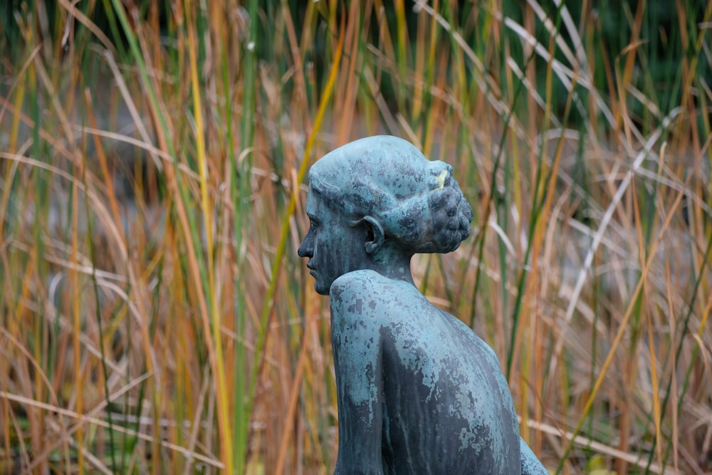 a statue of a boy in a field of tall grass