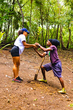 A diverse group of Rotary Climate Action Club members planting trees together in a lush community garden.