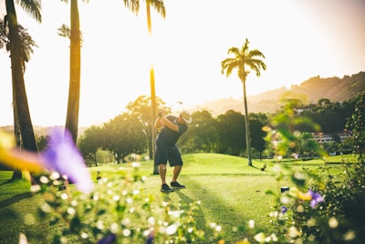 Close-up of a golfer’s swing mid-action, with a focused expression and sun setting behind.