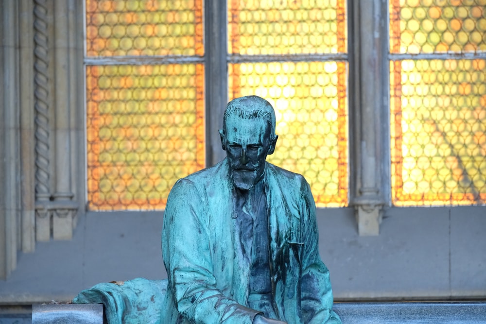 a statue of a man sitting in front of a window