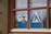 A window with wooden frames displays signs prohibiting caravans and camping. The blue signs highlight a crossed-out caravan and a tent symbol, both marked with a red diagonal line.