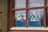 A window with wooden frames displays signs prohibiting caravans and camping. The blue signs highlight a crossed-out caravan and a tent symbol, both marked with a red diagonal line.