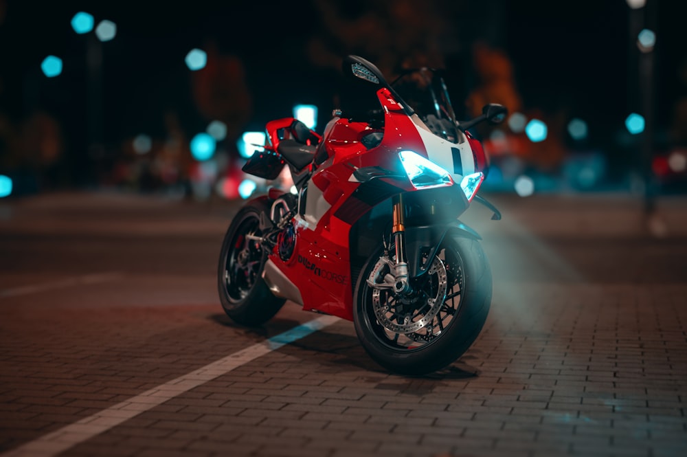 a red and white motorcycle parked on the side of a road