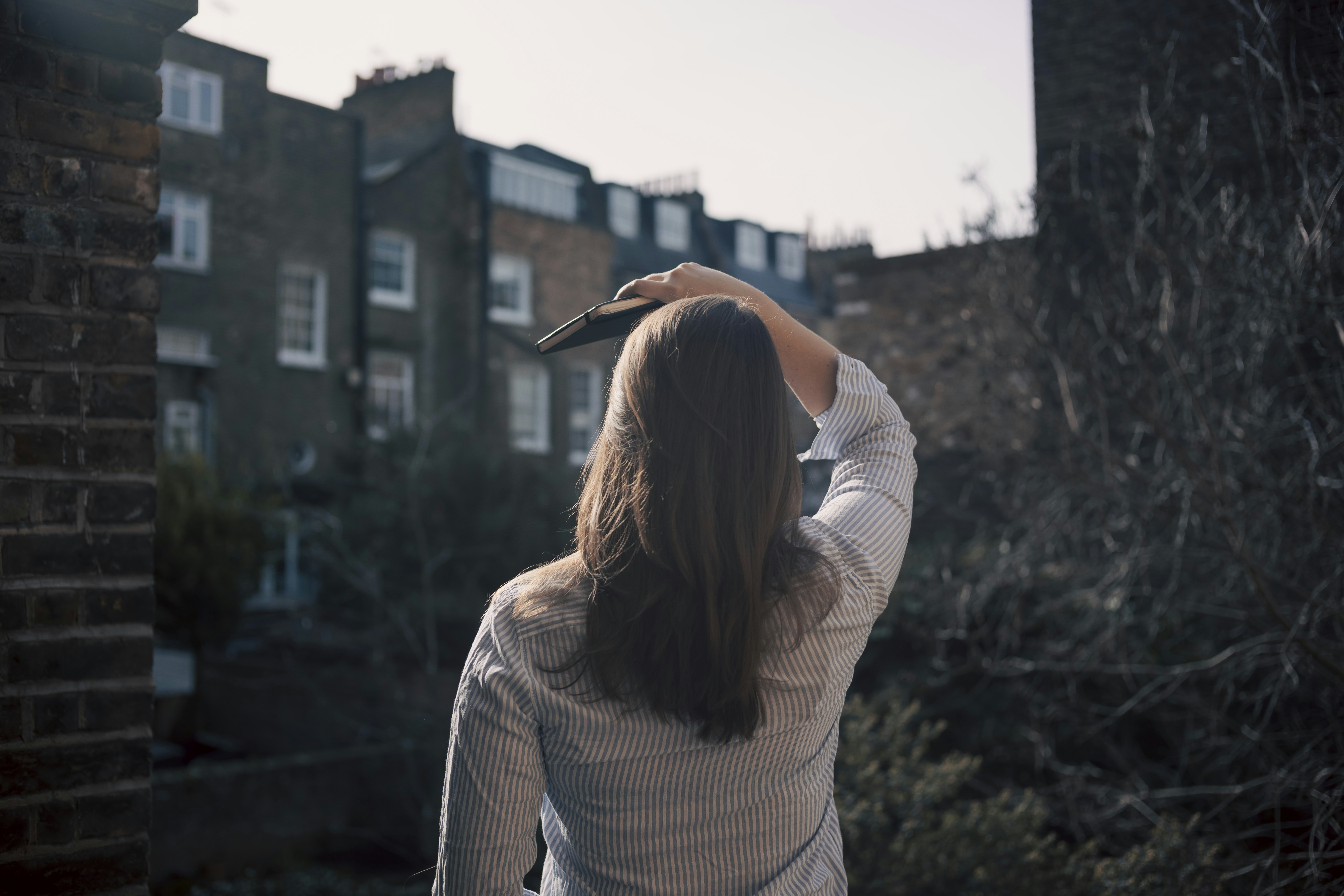 A woman standing in front of a brick building photo – Free Woman Image ...
