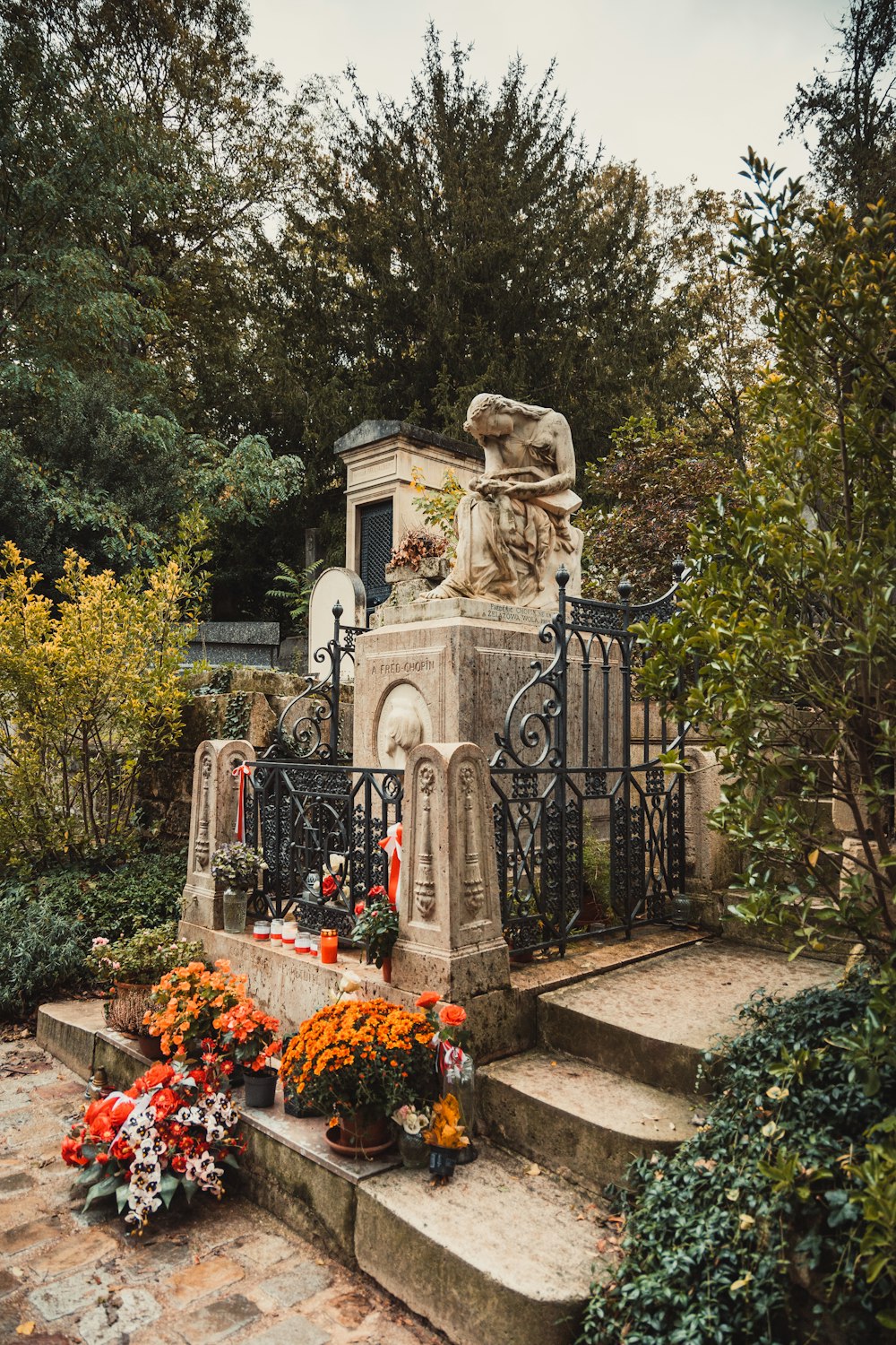 a cemetery with a statue and flowers in the foreground