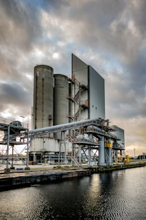 a large industrial building next to a body of water