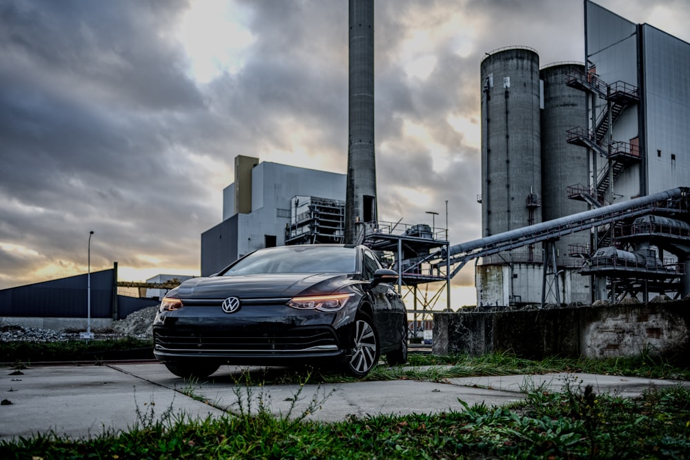 a black car parked in front of a factory