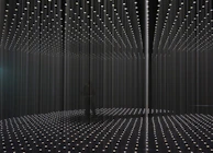 An installation art piece featuring intertwined metal and glass elements under soft spotlighting.