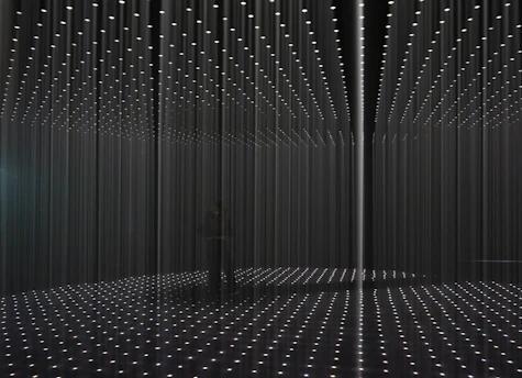 A large, striking photograph capturing the main installation of the exhibition, showcasing the artist's use of light and shadow.