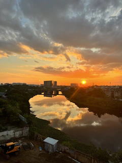 A vibrant sunset over a jungle landscape with a winding river reflecting the orange and green hues.