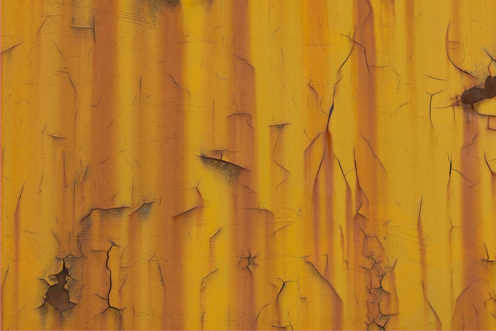 a close up of a yellow wall with peeling paint