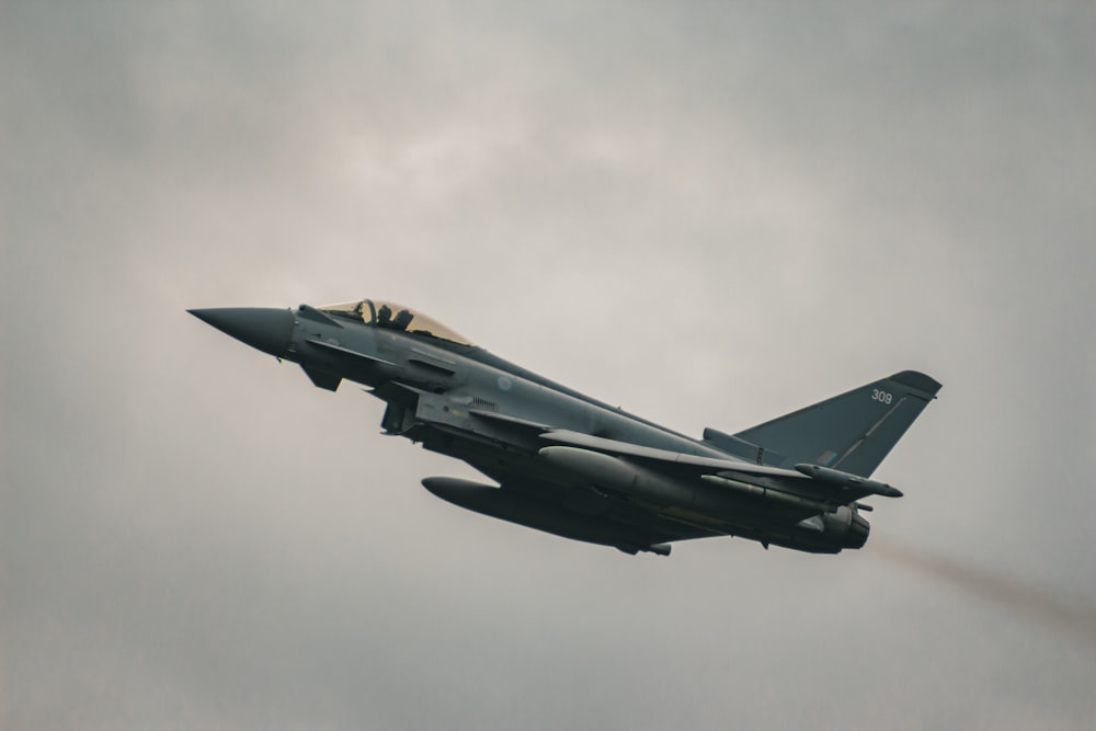 a fighter jet flying through a cloudy sky