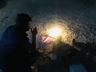 Traveler resting by a campfire, sipping water from a Xinky Tech bottle under a starry night sky.