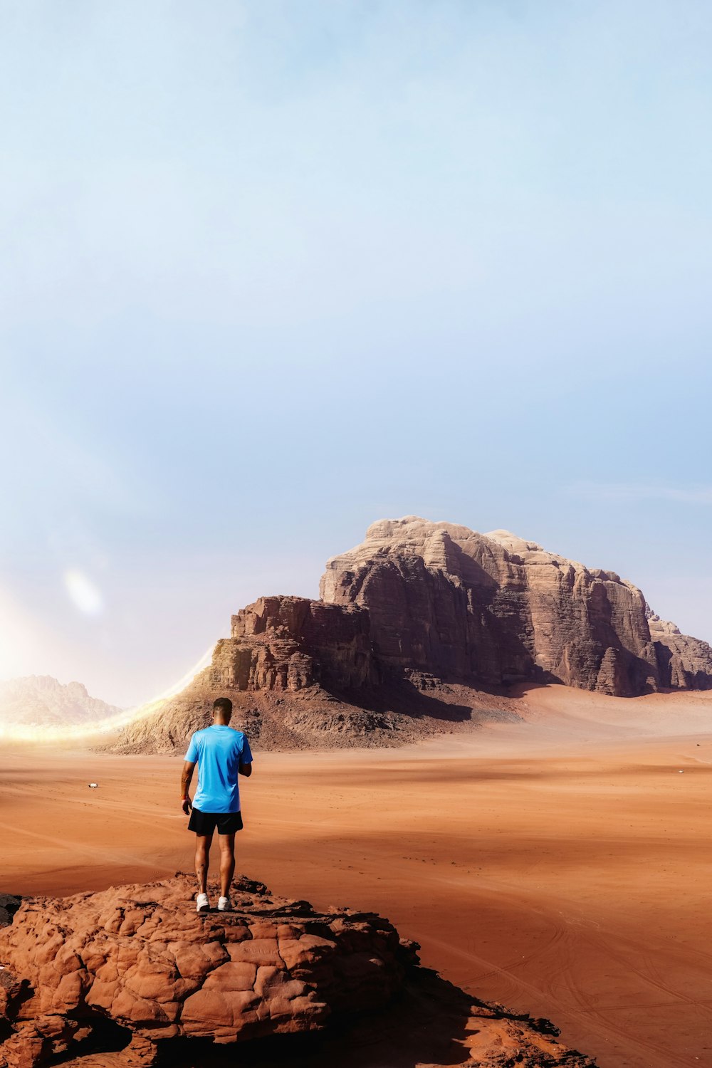 사막 한가운데의 바위 위에 서 있는 남자