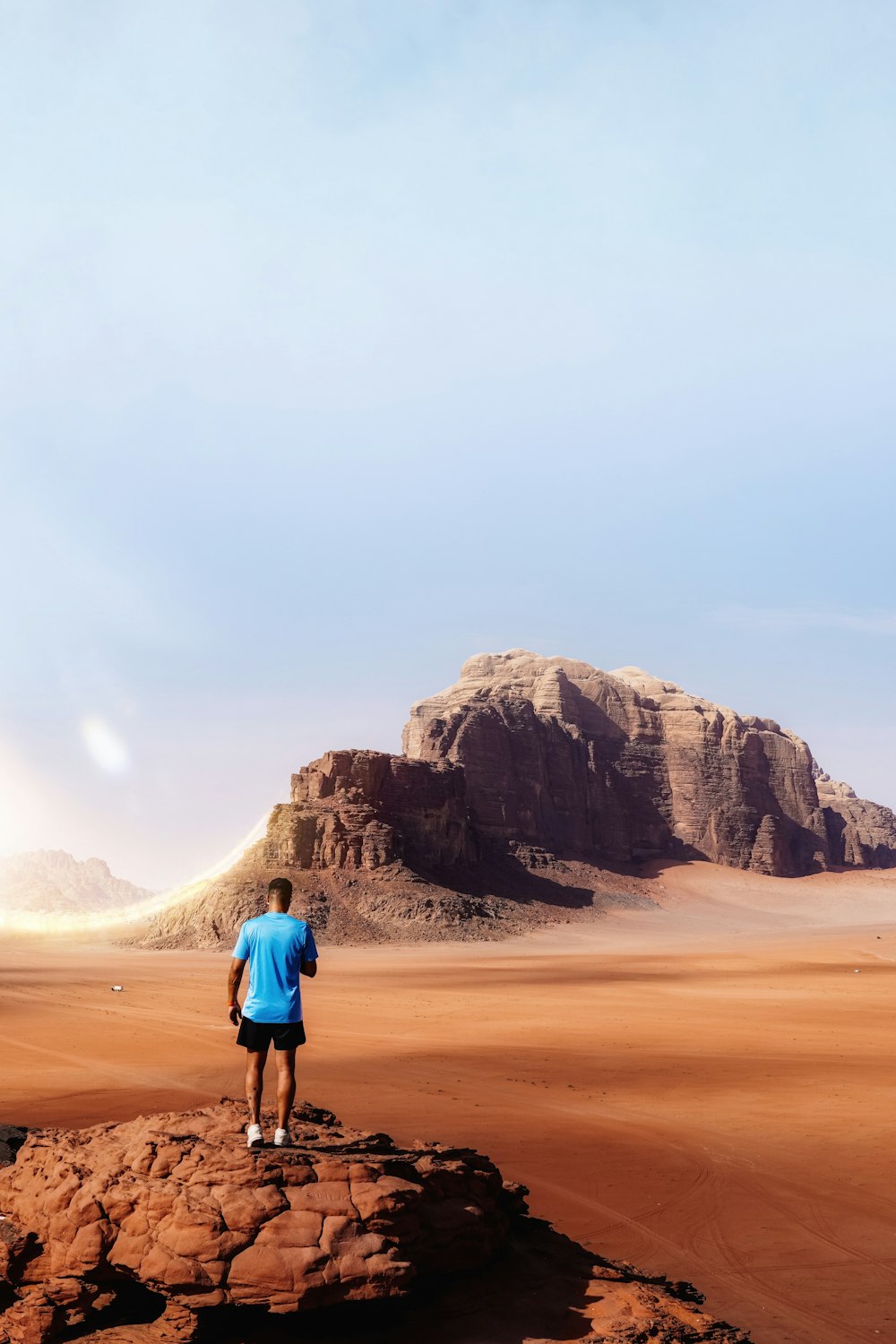 a man standing on a rock in the middle of a desert