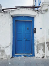 Technician in blue uniform repairing a modern home's front door with visible before-and-after sections.